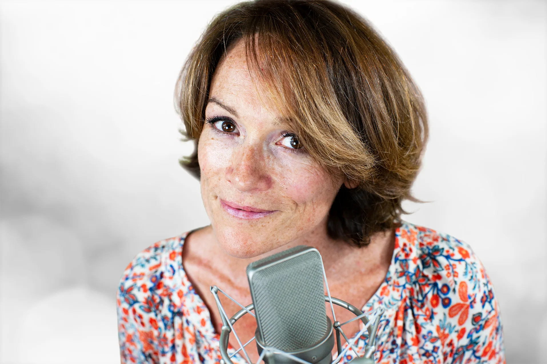 Een voice-over met koptelefoon spreekt een tekst in bij een professionele studiomicrofoon.